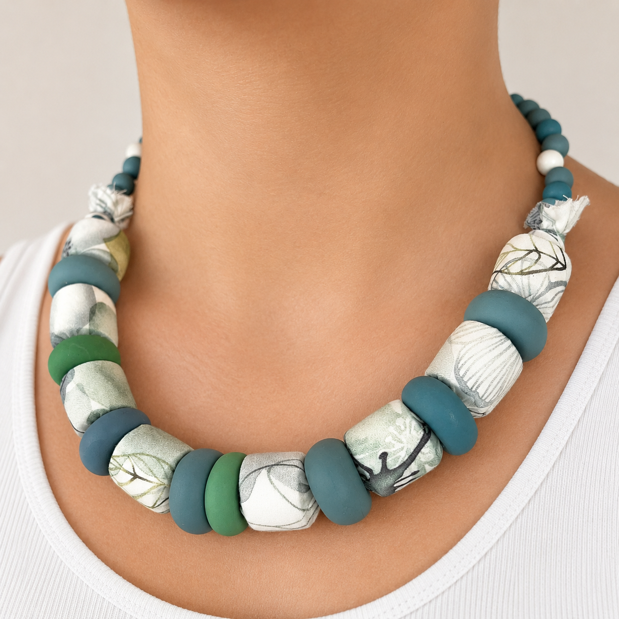 Collar Kaiora Lago de cuentas grandes textiles botánicas y lisas en tonos verdes y azules.