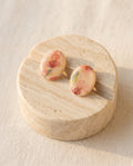 Pendientes ovalados Kaiora Rose con ilustración floral en tonos rosados y carmines.