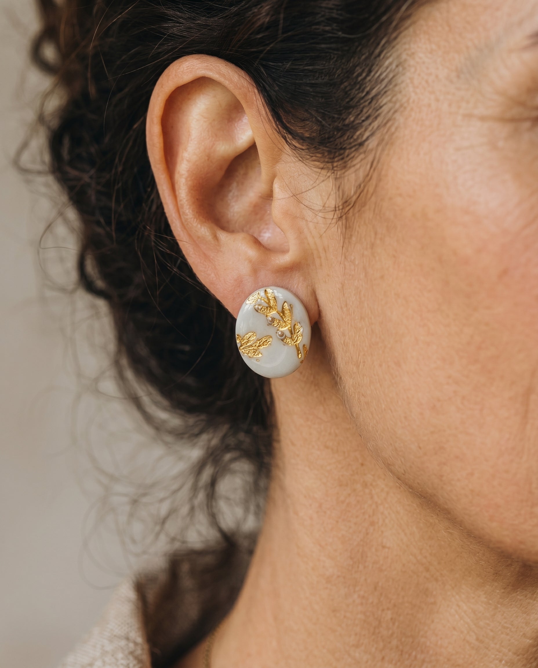 Pendientes stud Jardín Dorado Kaiora con diseño botánico de hojas doradas y perlas sobre base clara