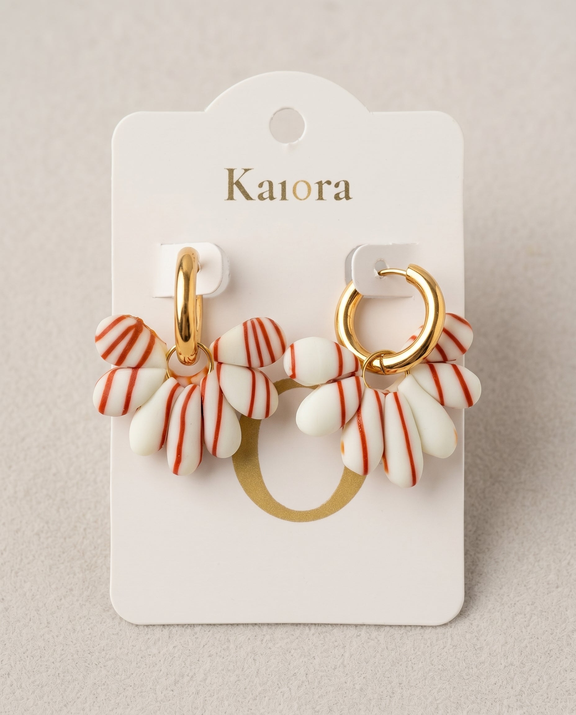 Pendientes Kaiora con pétalos blancos de rayas rojas y aros dorados de acero inoxidable.