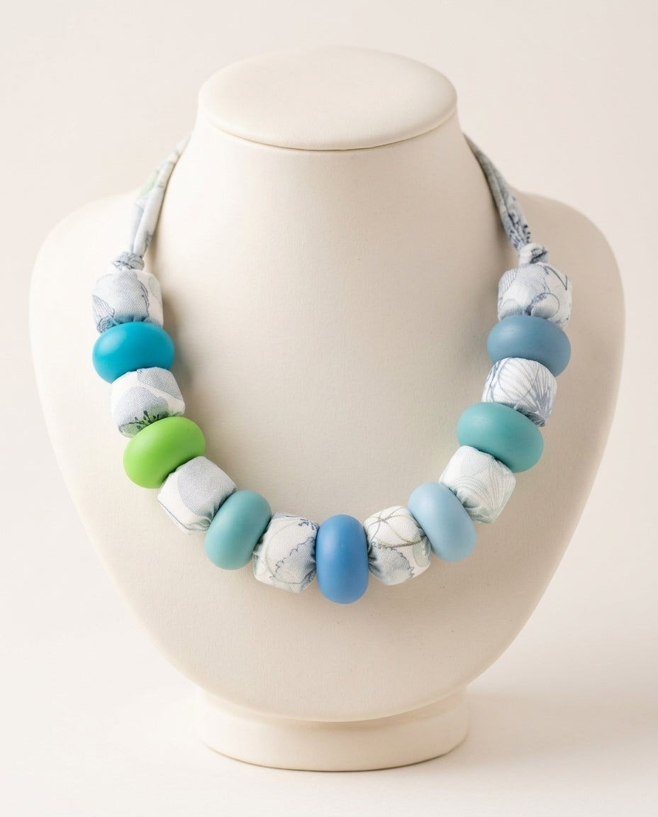 Collar Lago Kaiora con cuentas de tela estampada botánica y cuentas lisas azules y verdes.