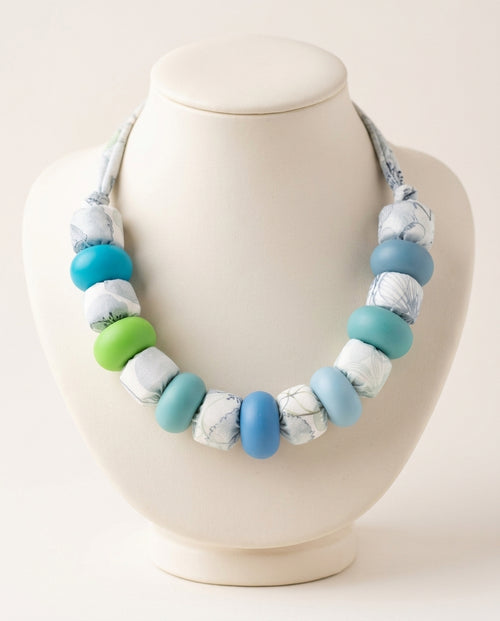 Collar Lago Kaiora con cuentas de tela estampada botánica y cuentas lisas azules y verdes.